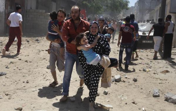 A Palestinian woman runs carrying a girl following what police said was an Israeli air strike on a house in Gaza city