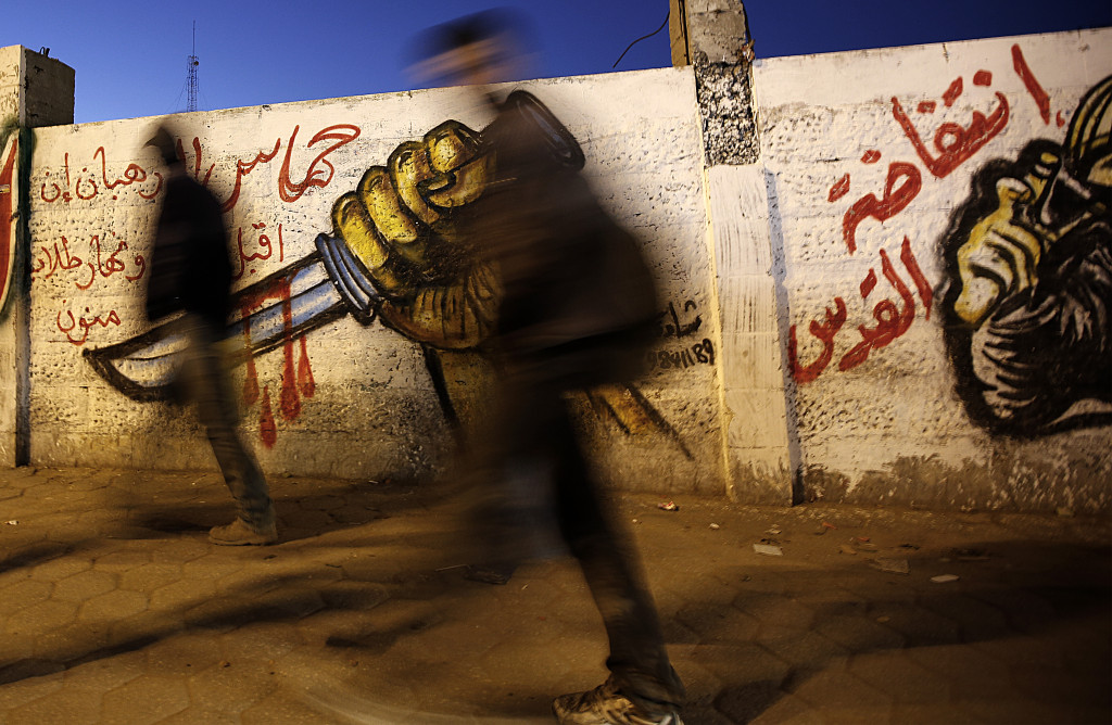 epa05117131 Palestinians walk in front of a graffiti depicting a hand holding a knife, in support of the third Palestinian 'intifada' or uprising, in the streets of Gaza City, 21 January 2016. EPA/MOHAMMED SABER