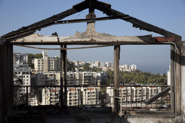 The Mediterranean sea and parts of the city can bee sen through a burned house following wildfires in Haifa, Israel, Friday, Nov. 25, 2016. Israeli firefighters reined in a blaze that had spread across the country's third-largest city and forced tens of thousands of people to flee their homes, but continued to battle more than a dozen other fires around the country for the fourth day in a row. (AP Photo/Ariel Schalit)
