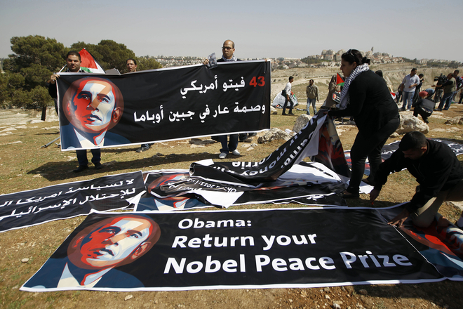Palestinian activists organise banners depicting U.S. President Obama at a protest camp in an area which connects the two parts of the Israeli-occupied West Bank outside Arab suburbs of East Jerusalem