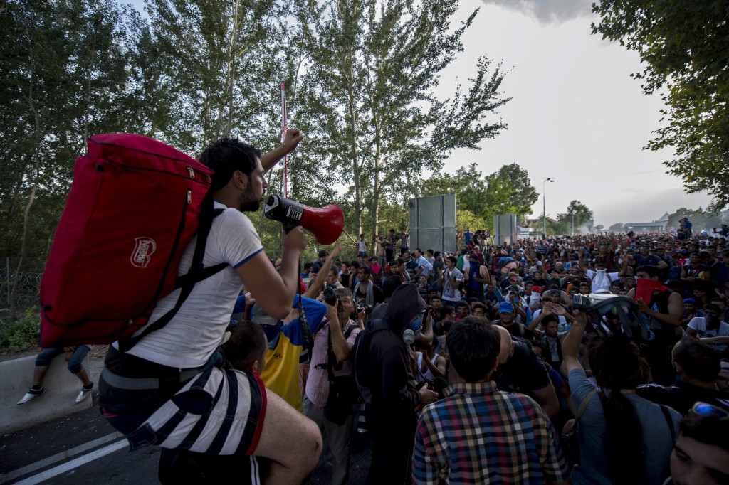 Röszke, 2015. szeptember 16. Egy migráns beszél hangosbeszélõn társa nyakában a Horgos-Röszke határátkelõhely magyar oldalán 2015. szeptember 16-án. MTI Fotó: Sóki Tamás