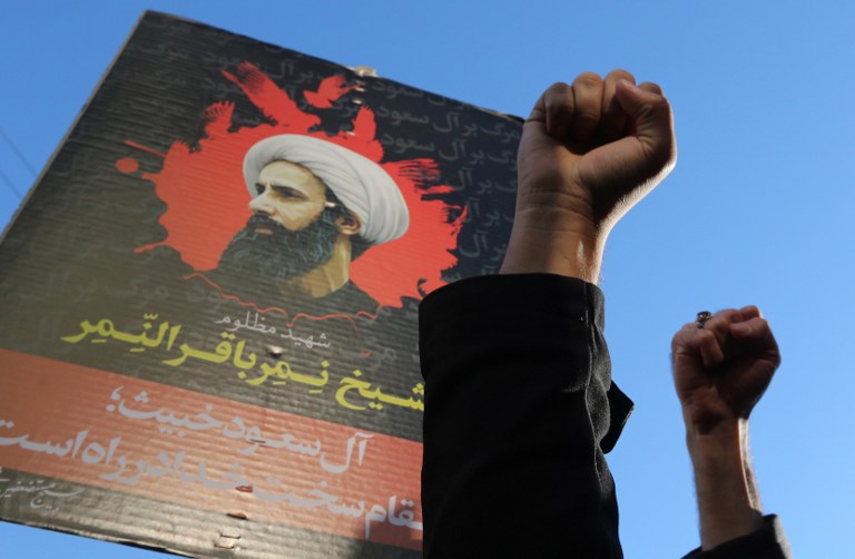 Iranian protesters raise their fists in front of a portrait of prominent Shiite Muslim cleric Nimr al-Nimr during a demonstration against his execution by Saudi authorities, on January 3, 2016, outside the Saudi embassy in Tehran. Iran and Iraq's top Shiite leaders condemned Saudi Arabia's execution of Nimr, warning ahead of protests that the killing was an injustice that could have serious consequences. AFP PHOTO / ATTA KENARE / AFP / ATTA KENARE