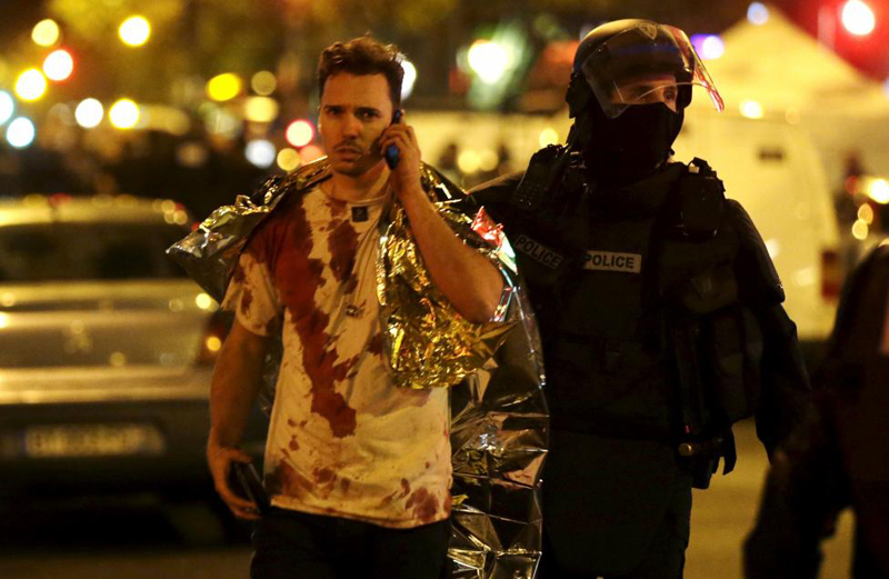 A French policeman assists a blood-covered victim near the Bataclan concert hall following attacks in Paris, France, November 14, 2015. Photo: REUTERS